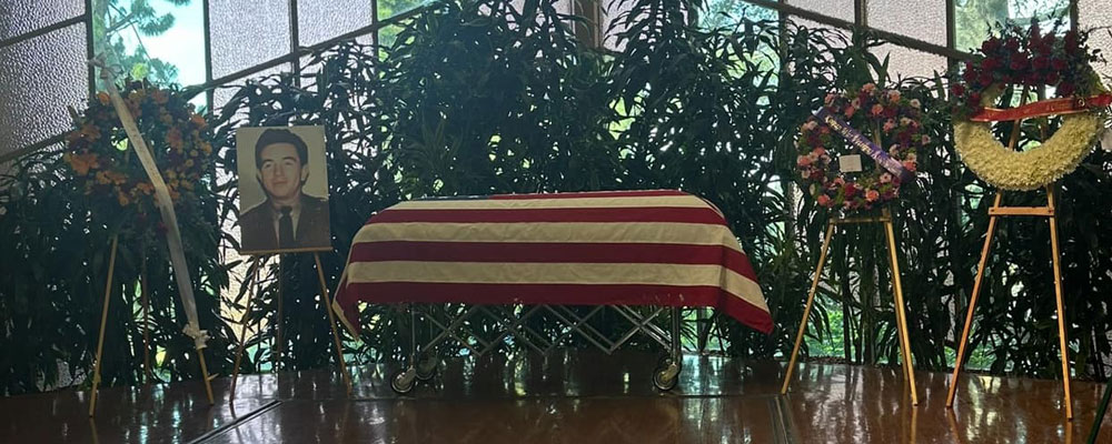 A military casket with a memorial photo and flowers at a funeral